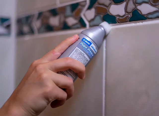 Detail ruky aplikující obnovovací fix na spáry mezi obklady.