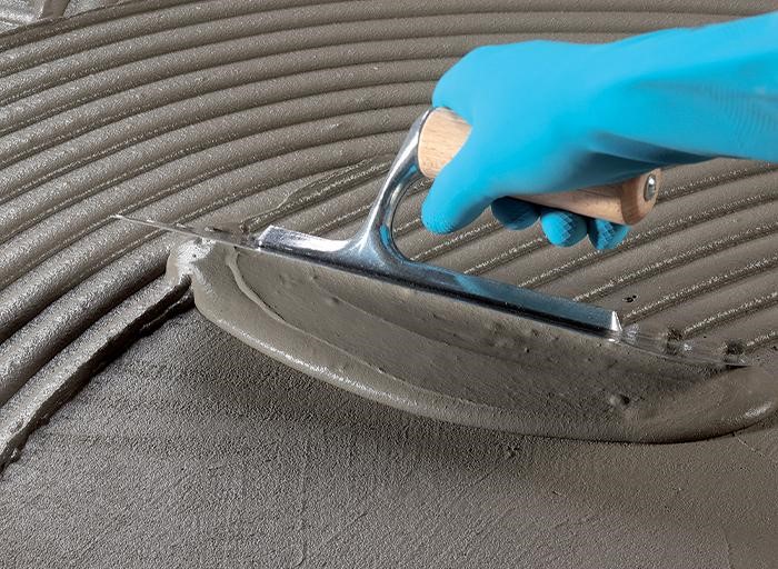 Aplikace lepidla hladítkem pro pevné uchycení.