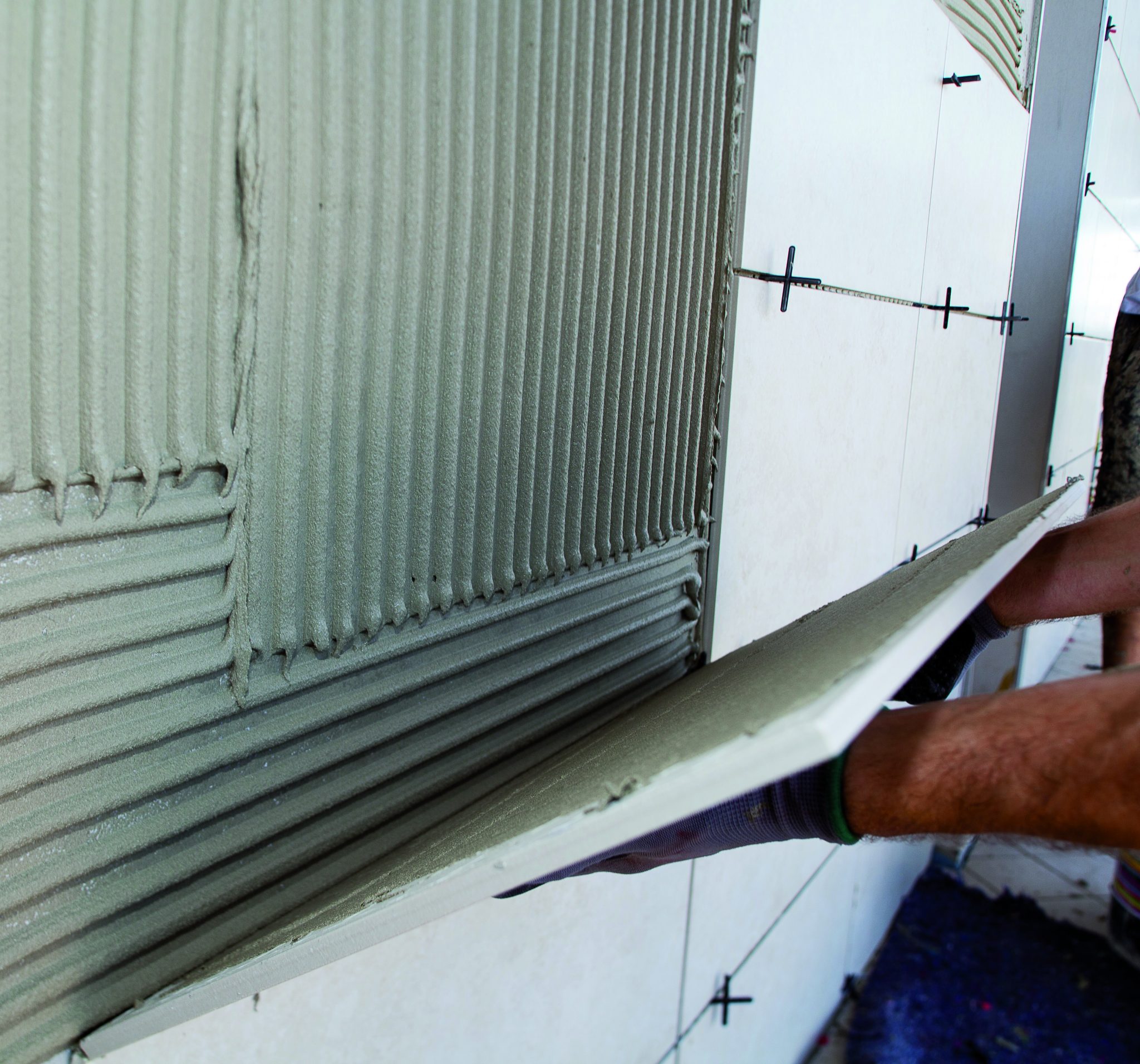 Lepení deformovatelným cementovým lepidlem na betonový podklad.