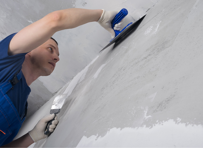 Řemeslník nanáší betonovou stěrku na stěnu